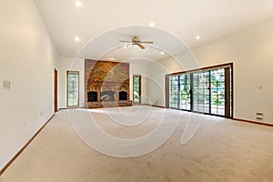 Very large empty living room with brick fireplace.