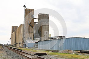 Very large working agricultural farm community feed grain and corn silo building next to railroad track in rural heartland america