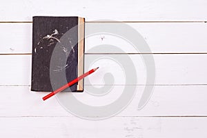 Very old black book on a white rustic wooden background. space for text.