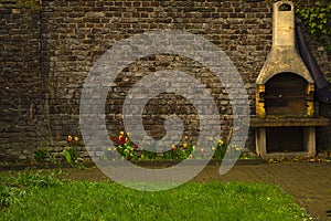 Very old brick wall with built-in grill, bright tulips on the background of old brick.