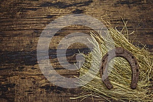 Very old cast iron metal horse horseshoe on hay. Good luck symbol, St.Patrick`s Day concept. Antique wooden background, horse
