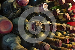 Very old and dusty bottles stacked in warehouse. Pile of very old dusty wine bottles.