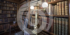 Very old library, 16th Century bookshelves with old fashioned light