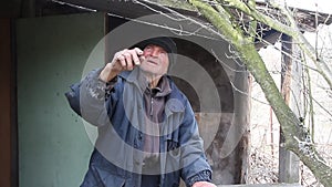 A very old man inspects garden trees in the spring before flowering removes extra branches preparing for the new season