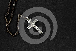 Very old metal rosary with silver cross placed on black background surface