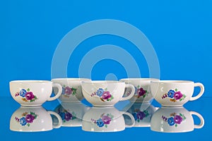 Very old porcelain tea set on blue reflection background