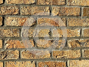 A very old retro style cracking and crumbling orange and red brick wall in a warehouse building alley showing bright detailed