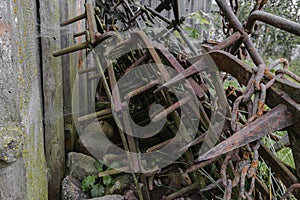 Very old and rusty harrows places near barn wall at countryside