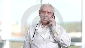 Very old senior physician talking on phone.