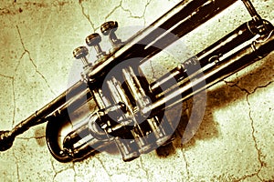 A very old trumpet, ancient of the 30s,on an ancient wall with cracks