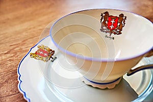 Very old vintage cup with a plate on a wooden table, both with `Danzig` written on it underneath the city`s coat of arms