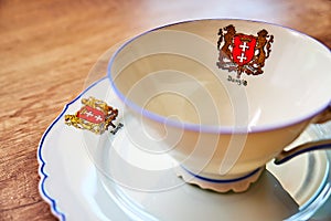 Very old vintage cup with a plate on a wooden table, both with `Danzig` written on it underneath the city`s coat of arms photo