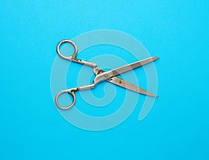 Very old vintage metal tailor scissors on a blue background
