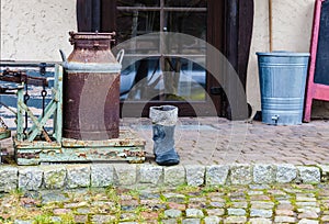 Very old wellingtons and copper bottle standing outside