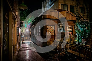 Very old wooden wagon with used books for sale inside, used as books shop, at night, dimly illuminated from behind