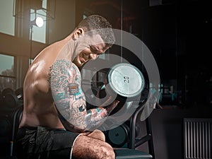 Very power athletic guy bodybuilder , execute exercise with dumbbells, in dark gy,