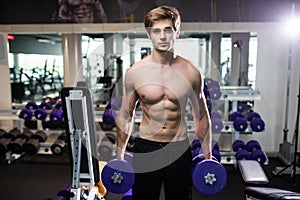 Very power athletic guy , execute exercise with dumbbells, in gym hall