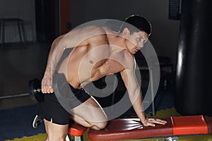 Very power athletic guy , execute traction with dumbbells, exercise on broadest muscle of back, in sport hall.