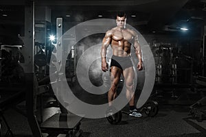 Very power athletic guy standing with barbell workout in the gym