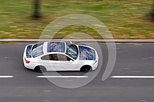 Molto velocemente gestione bianco ecologico soleggiato elettrico auto sul la città strade. immagine è un interessato forte movimento sfocatura effetto 