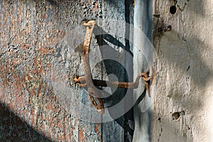 Very rusty door hook closing a wooden door, closeup. An old wooden gate locked with an equally old rusty hook . Vintage background