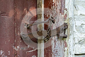 Very rusty padlock closing a wooden door, closeup. An old wooden gate locked with an equally old rusty padlock. Vintage background