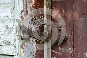 Very rusty padlock closing a wooden door, closeup. An old wooden gate locked with an equally old rusty padlock. Vintage background