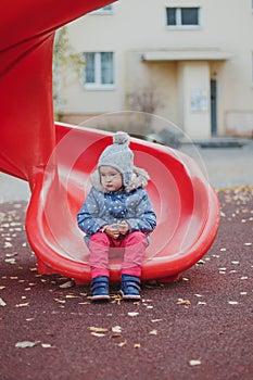 Very sad child girl sitting on a hill in the playground