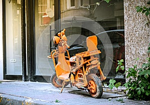 Very shabby diy modified scooter, retro city bike, painted all orange, phosphorous, stays as an offbeat object on the street
