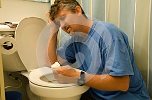 Very sick man throwing up at the toilet