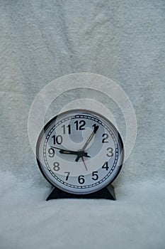 A very simple round black and grey clock against empty background