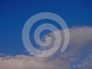 Very small and light propeller plane flying at high altitude, in the background of blue sky, view from bottom from the back