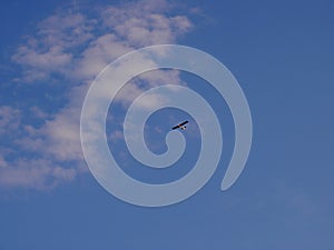 Very small and light propeller plane flying at high altitude, in the background of blue sky, view from bottom from the front