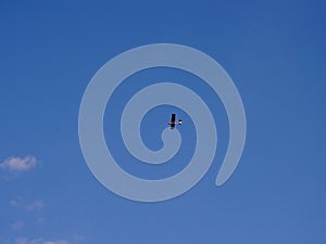 Very small and light propeller plane flying at high altitude, in the background of blue sky, view from bottom from the side