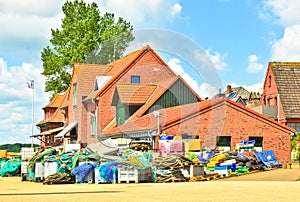 A very small and tiny harbor in Maasholm, Germany, with a huddle of traditional fishing equipement in front of a red house