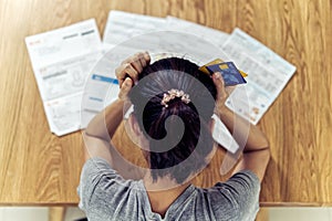 Very stressed young sitting Asian woman hands holding the head worry about find money to pay credit card debt.