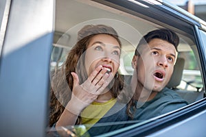 Very surprised man and woman looking out of the car.