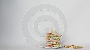 A very tall sandwich on a white isolated background on which another sandwich falls. big sandwich on white background