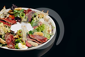 Very tasty salad with roast beef on a black background
