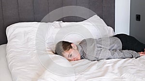 A very tired schoolgirl falls on a big bed in white underwear.