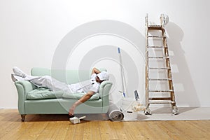 Very tired worker concept, painter man sleeps on the couch photo