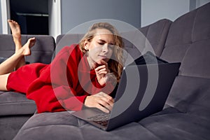 Very tired young woman, burning the midnigh oil - working late at night on her laptop computer, at home, sitting on sofa