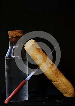 Una barra de pan de pan un cuchillo transición eso próximo sobre el una botella 