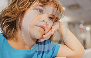 Very unhappy sad kid looks away. Boy waiting for someone in the cafe.