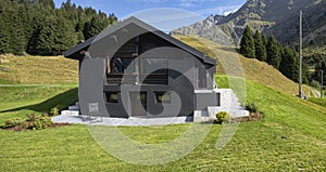 A very unusual Swiss mountain chalet because it is black and made of wood. Around a beautiful green summer meadow