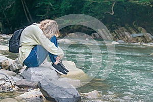 very upset girl tourist on the bank of a mountain river is crying