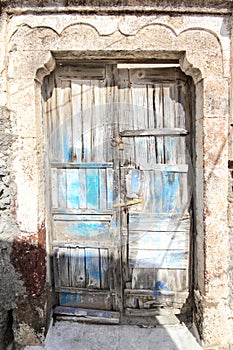 A very worn and battered old blue door