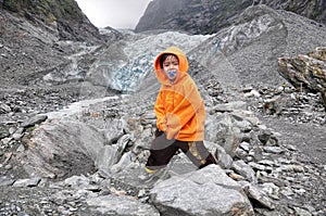 Asian boy posing cheekily in front of franz joseph glacier, New Zealand photo