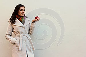 Woman in a coat holding a bitten red juicy apple