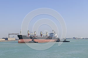 Vessel approaching to berth with tugs assistance. Mooring operations. Bulker. Dry cargo ship